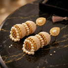Costume Jhola Dool (E67-0711) in pearl and gold with jhumka design, styled on a marble surface – Anjali Jewellers